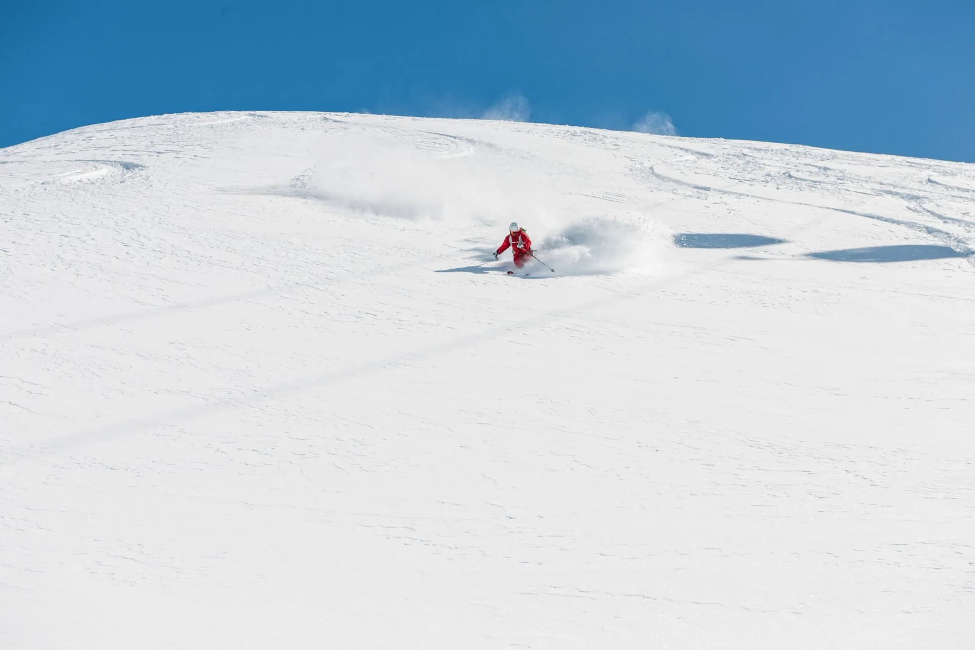 Freeride skier going fast downhill. Stock picture of a freeride skier that is skiing fast downhill in deep powder snow. There is a beautiful clear blue sky in the background. The location is Hochgurgl