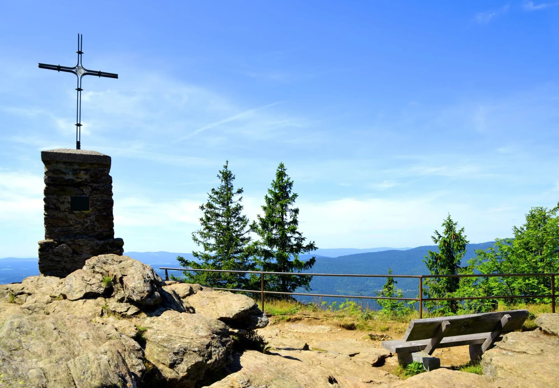 Cross and wooden bench on the summit of a mount Grosser Falkenstein in the National park Bayerische Wald, Germany.