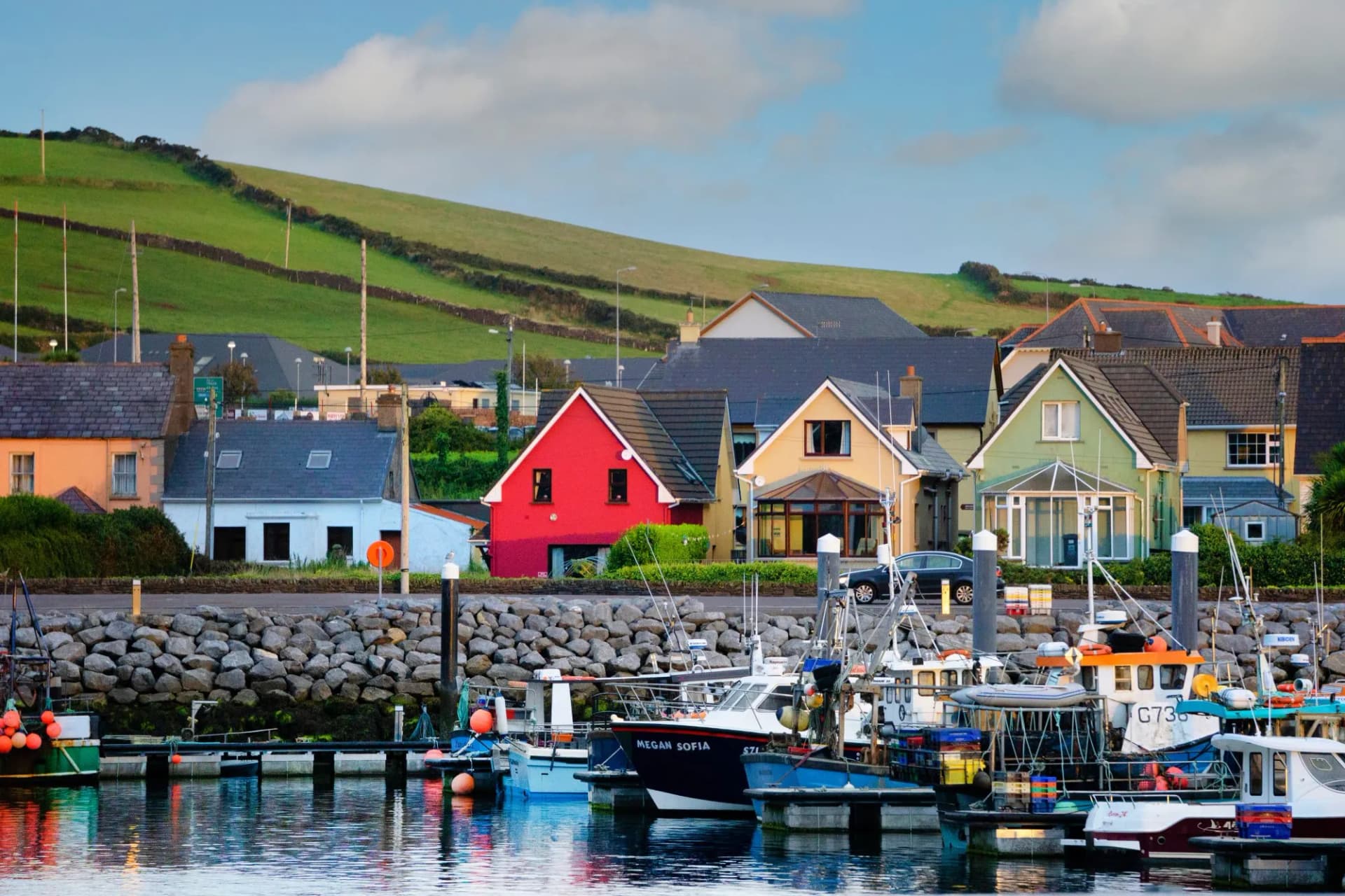 Various colorful houses and boats lining DIngle Bay in Dingle, Ireland.