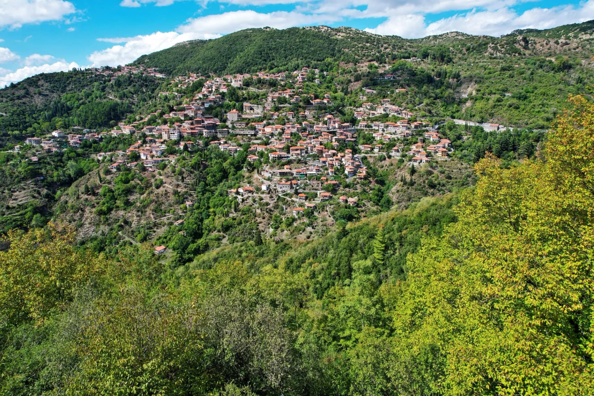 Aerial view of Lagkadia, a traditional mountain village in Arcadia, Greece. Nestled in lush green hills, its picturesque red-roofed houses.